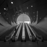 grayscale photography of person on escalator